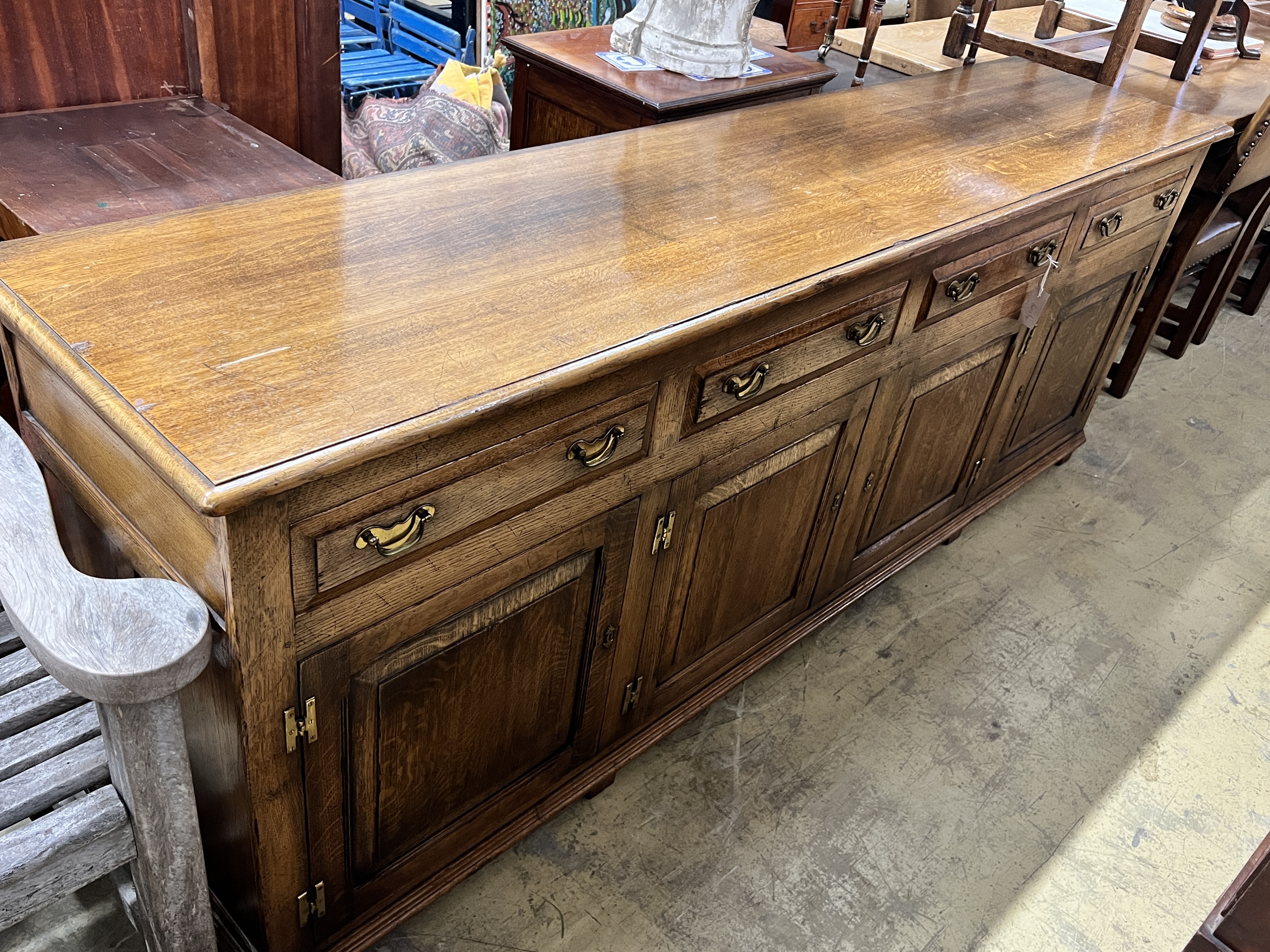 A large reproduction 18th century style oak sideboard, with four drawers and two pairs of hinged panelled cupboards, length 220cm, depth 50cm, height 83cm